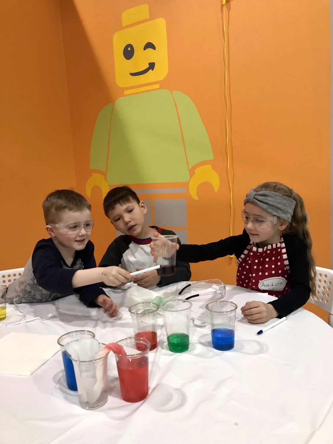Students in safety goggles running a colour-changing science experiment